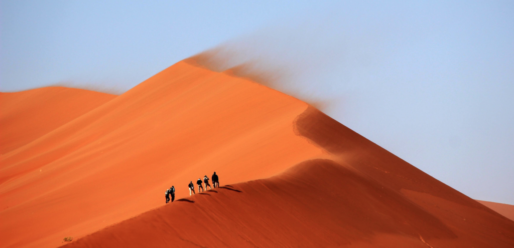 Alt: Best Morocco Desert Tours - camel caravan crossing the Sahara at sunset
